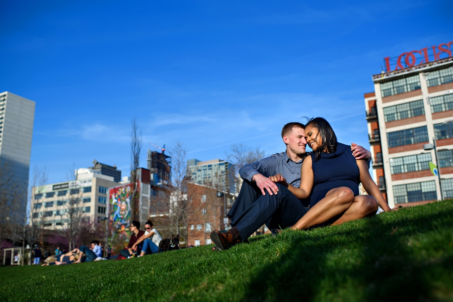 An engaged couple hang out in the park along the schuylkill river trail.